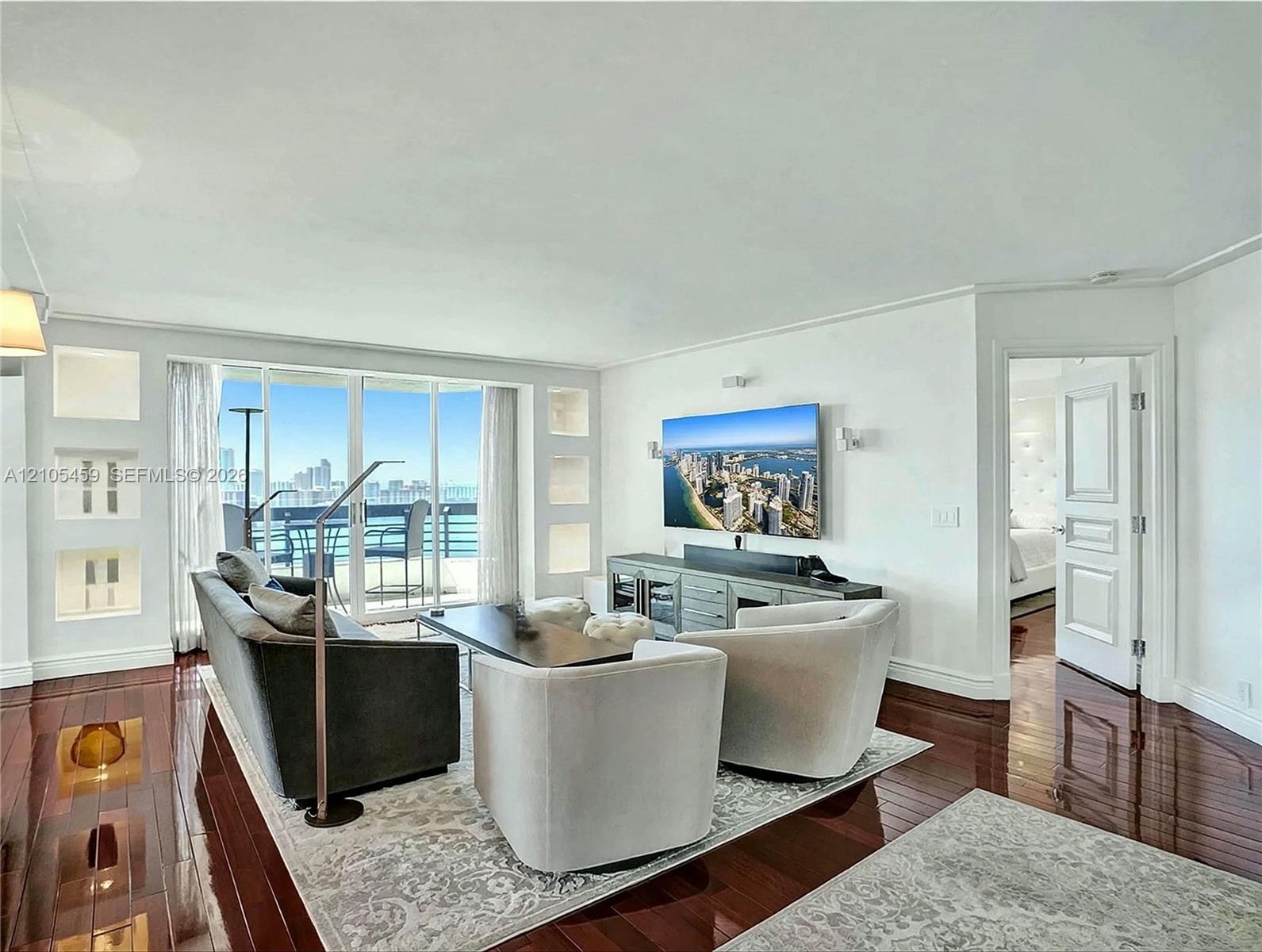 Rich wood-finish flooring throughout, integrated wall niches, and sliding glass doors opening to an outdoor living space