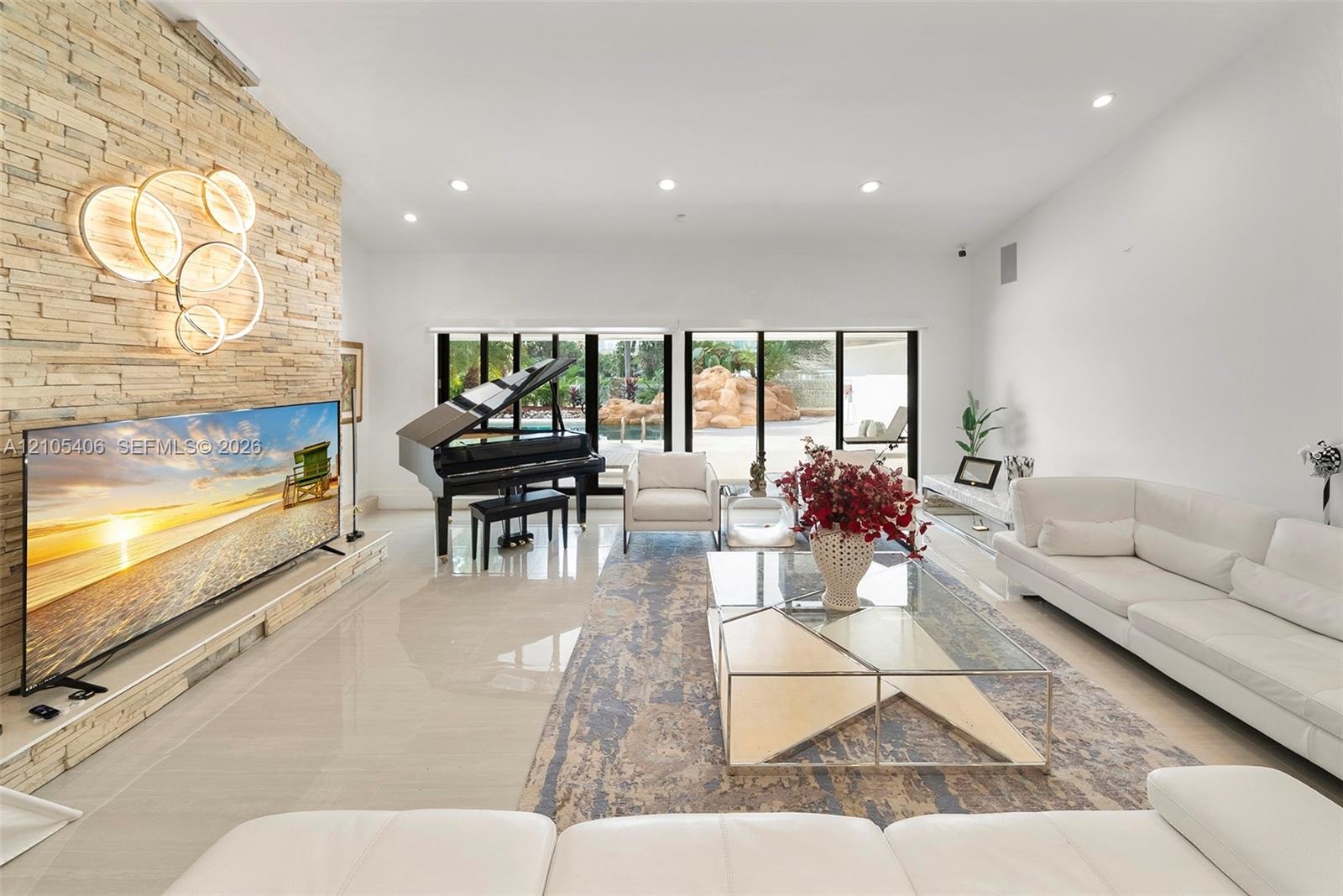 Polished tile flooring, a stacked stone accent wall, recessed lighting, and expansive sliding glass doors