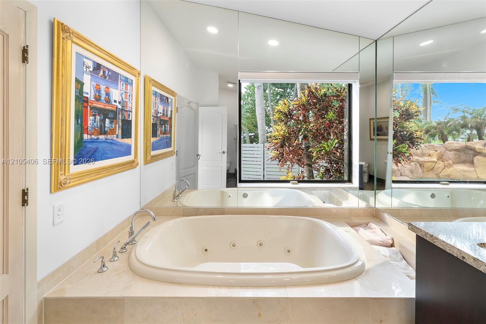 Built-in jetted tub with polished chrome fixtures, integrated into a stone-finish countertop