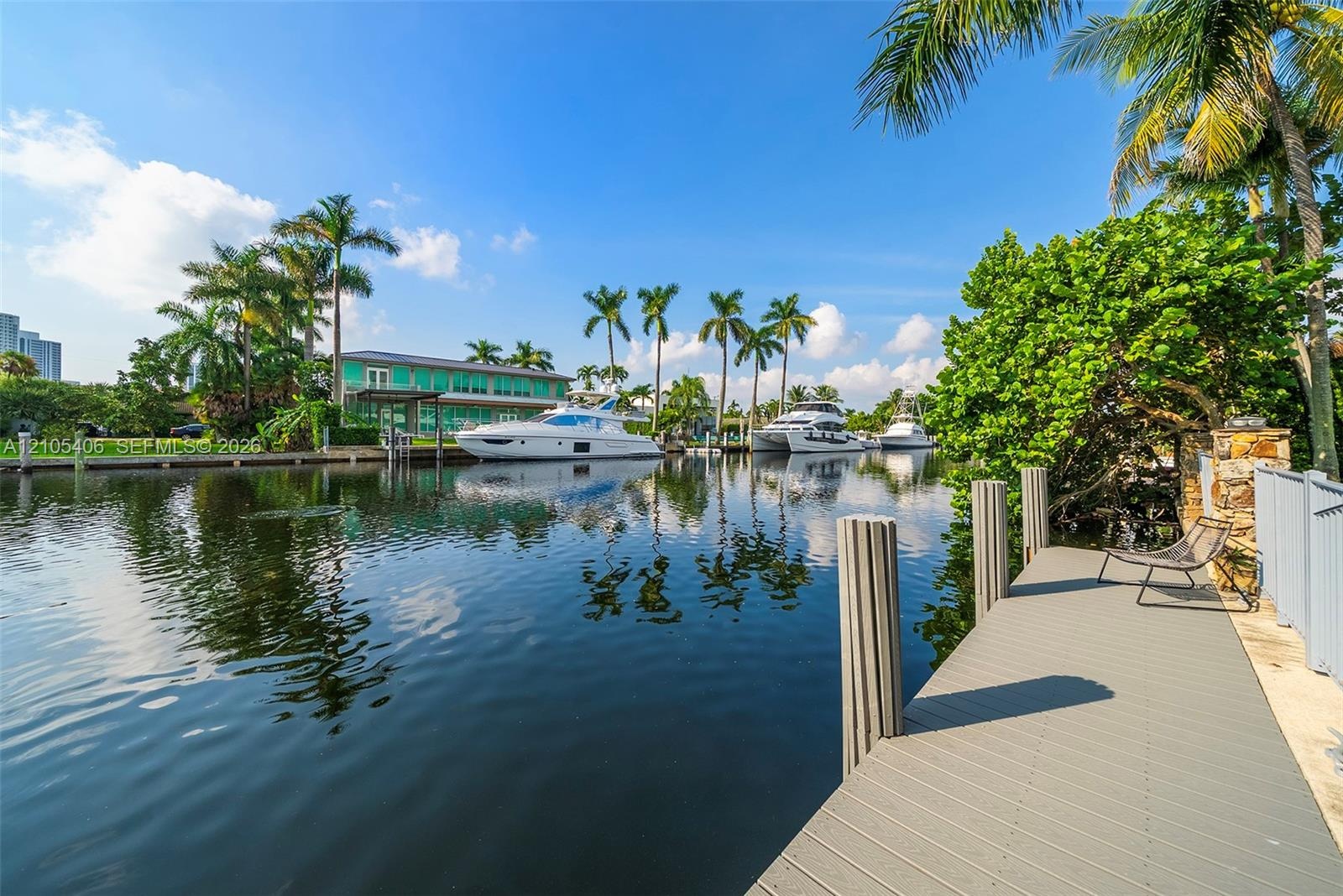 Waterfront property featuring a private dock with marine pilings, mature palm trees, and lush landscaping