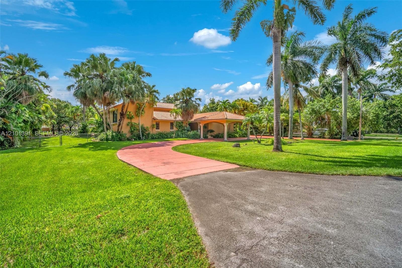 Mediterranean-style residence with a terracotta tile roof, stucco exterior, and a porte-cochere entry