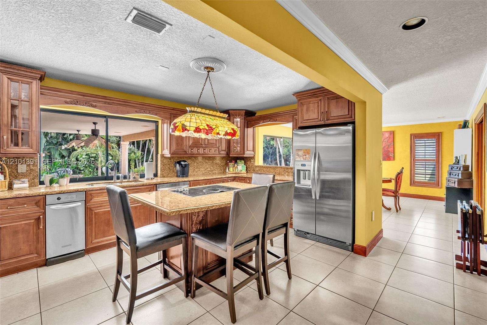 Kitchen featuring wood cabinetry, stainless steel appliances, a built-in cooktop island, and a large window