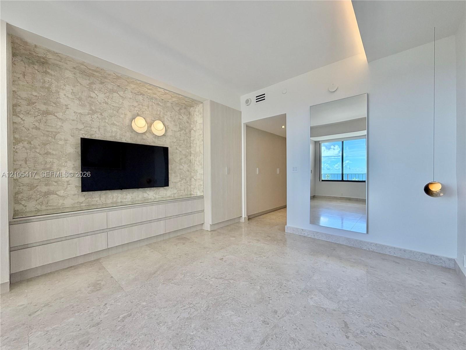 Built-in media console with integrated storage, textured wall finish, and two wall-mounted light fixtures