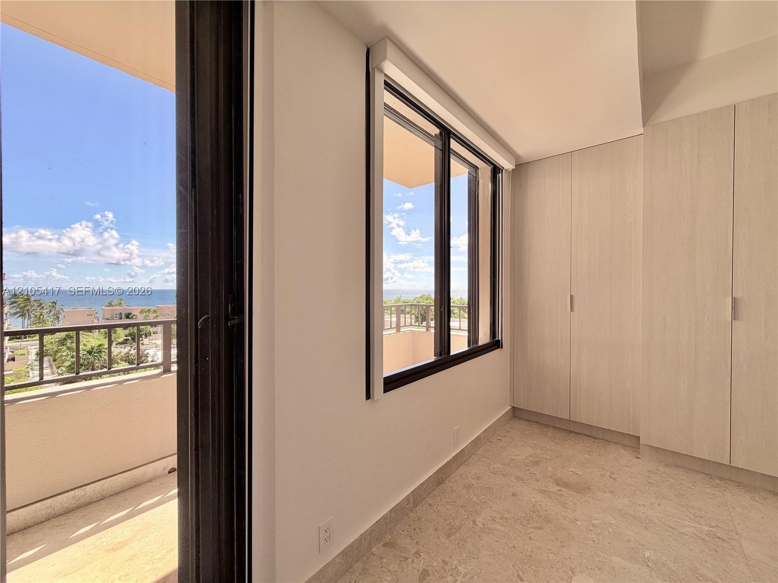Full wall of built-in cabinetry, large window, and direct balcony access