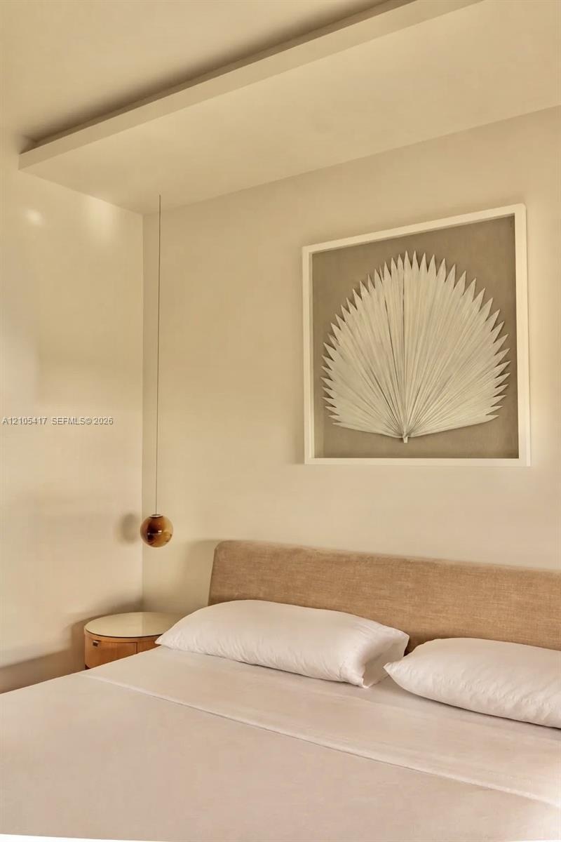 Recessed ceiling panel, fabric upholstered headboard, suspended spherical light fixture, and wood-finish side table with white top