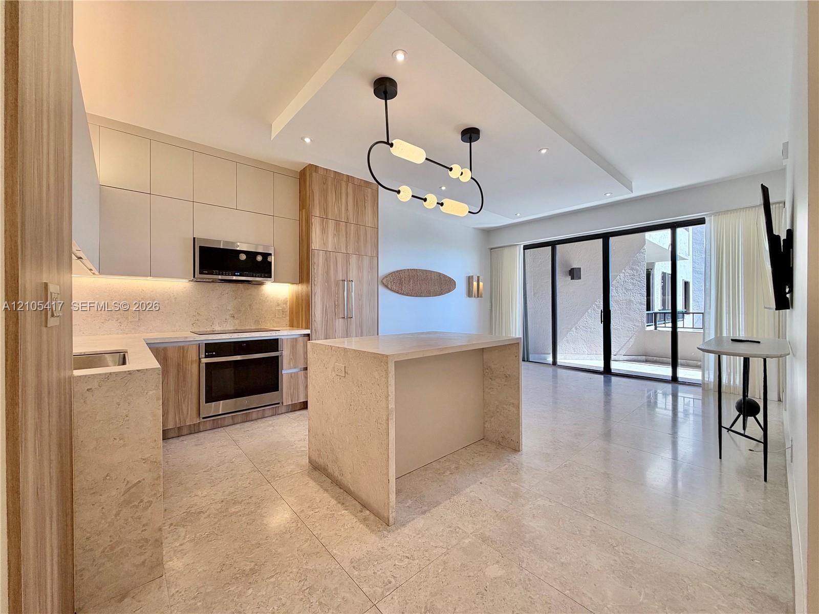 Contemporary kitchen with integrated appliances, light-toned cabinetry, and a stone-clad island