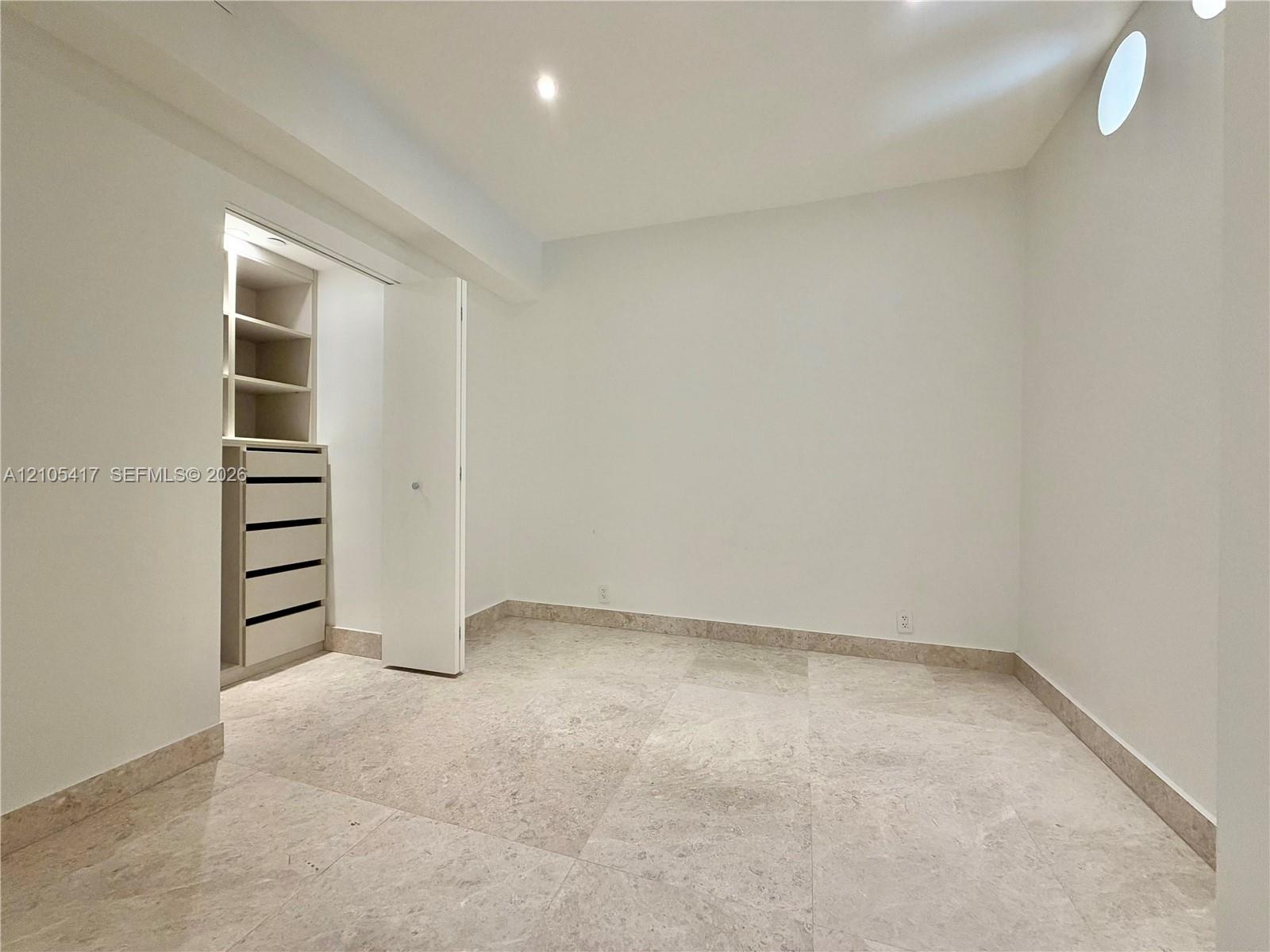 Recessed lighting, built-in closet storage with drawers, built-in shelving, a round window, and large format tile flooring