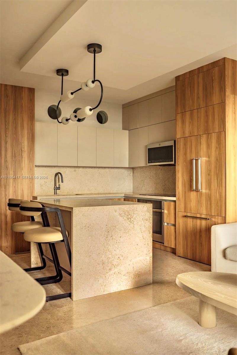 Kitchen with wood-finish cabinetry, integrated refrigerator, and built-in microwave