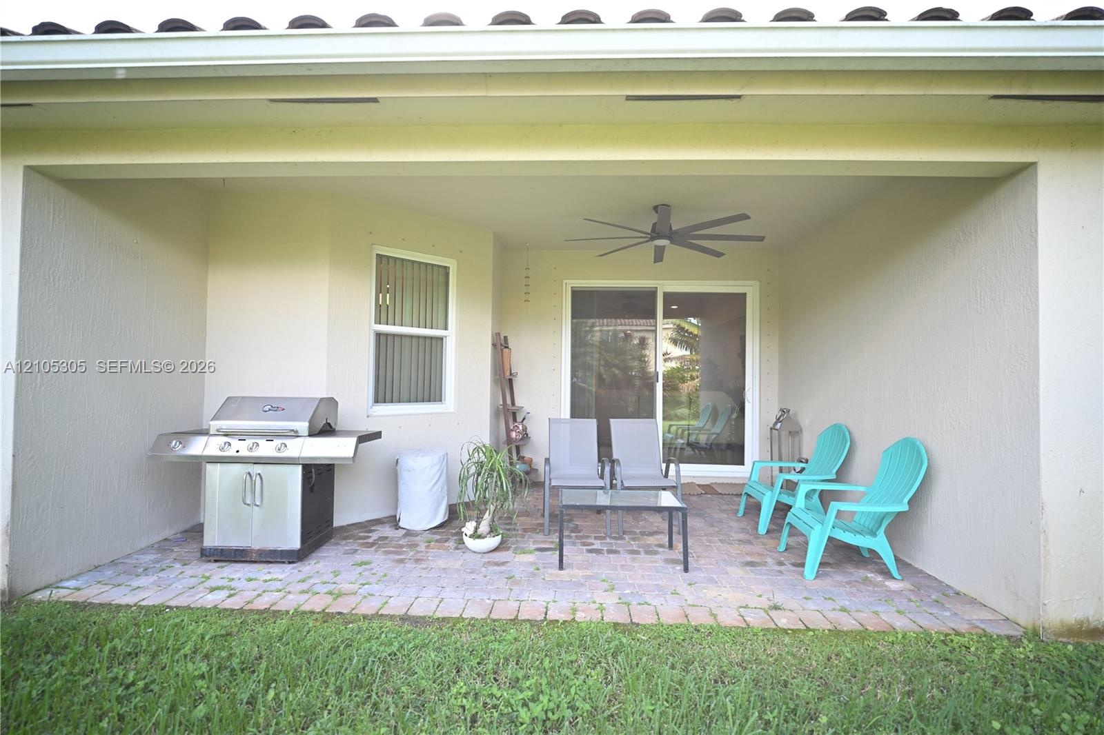 Covered patio with brick paver flooring, sliding glass door, and ceiling fan