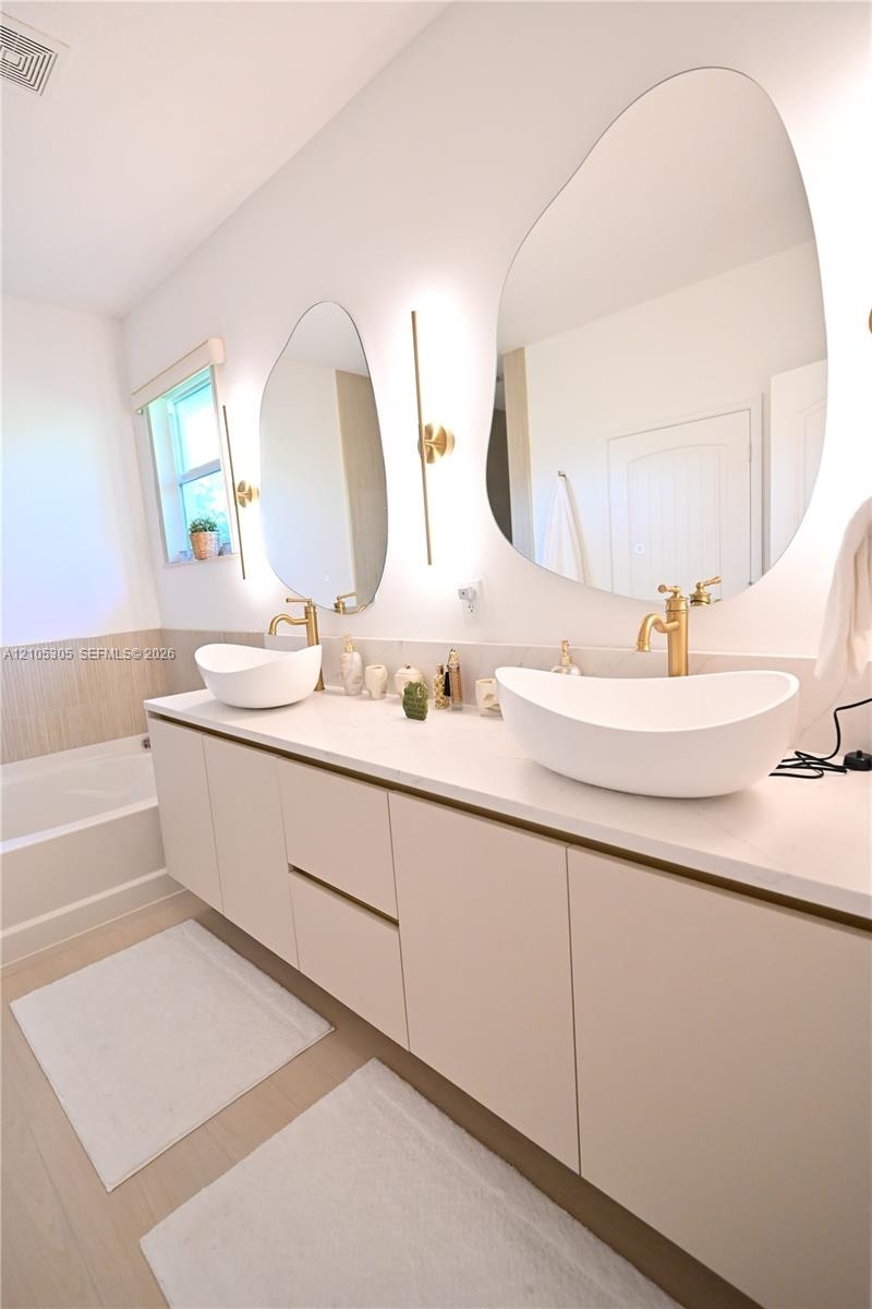 Floating vanity with dual vessel sinks, wall-mounted fixtures, and integrated lighting