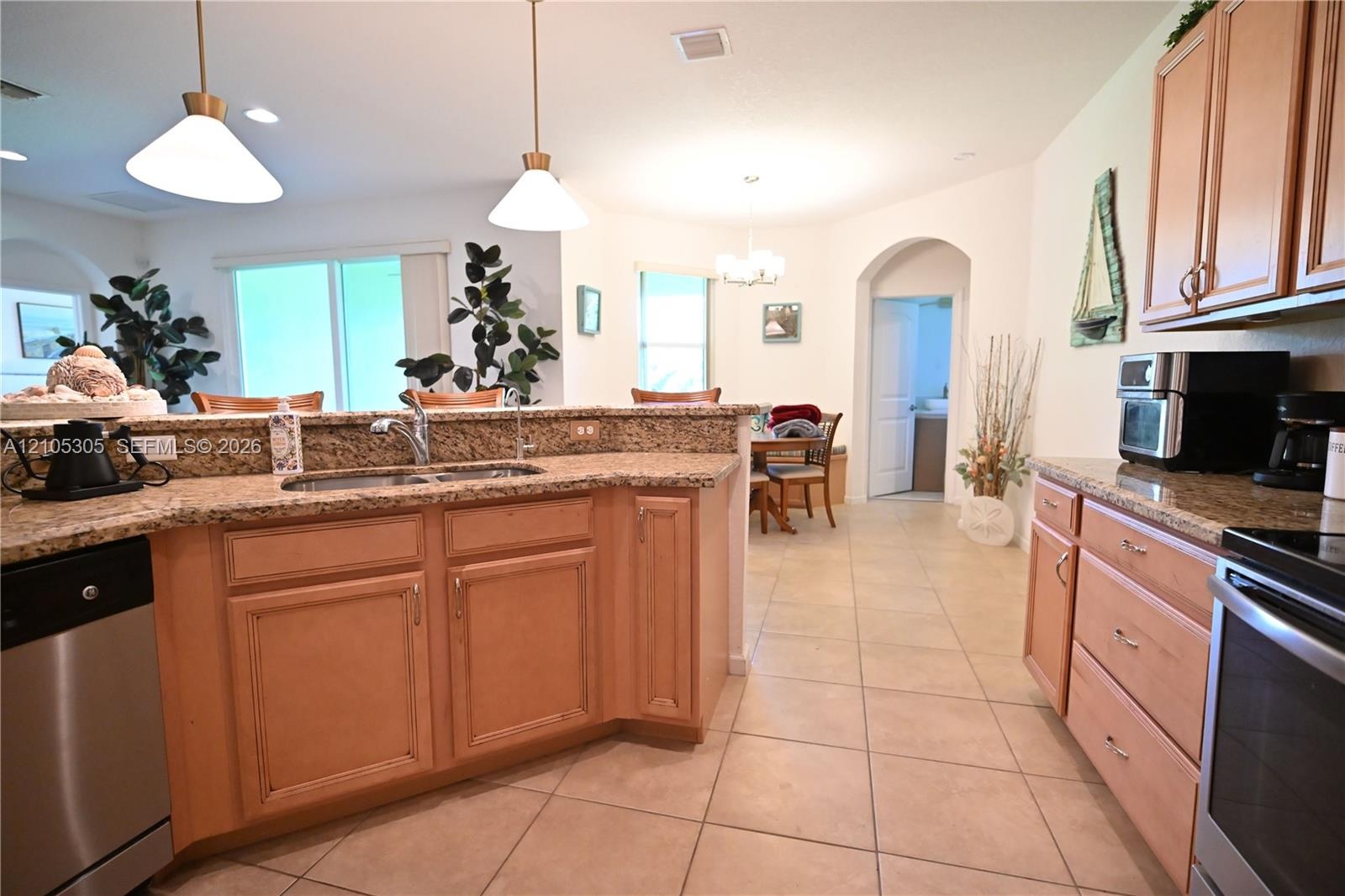 Kitchen featuring light wood-finish cabinetry, stainless steel appliances, and a double basin sink