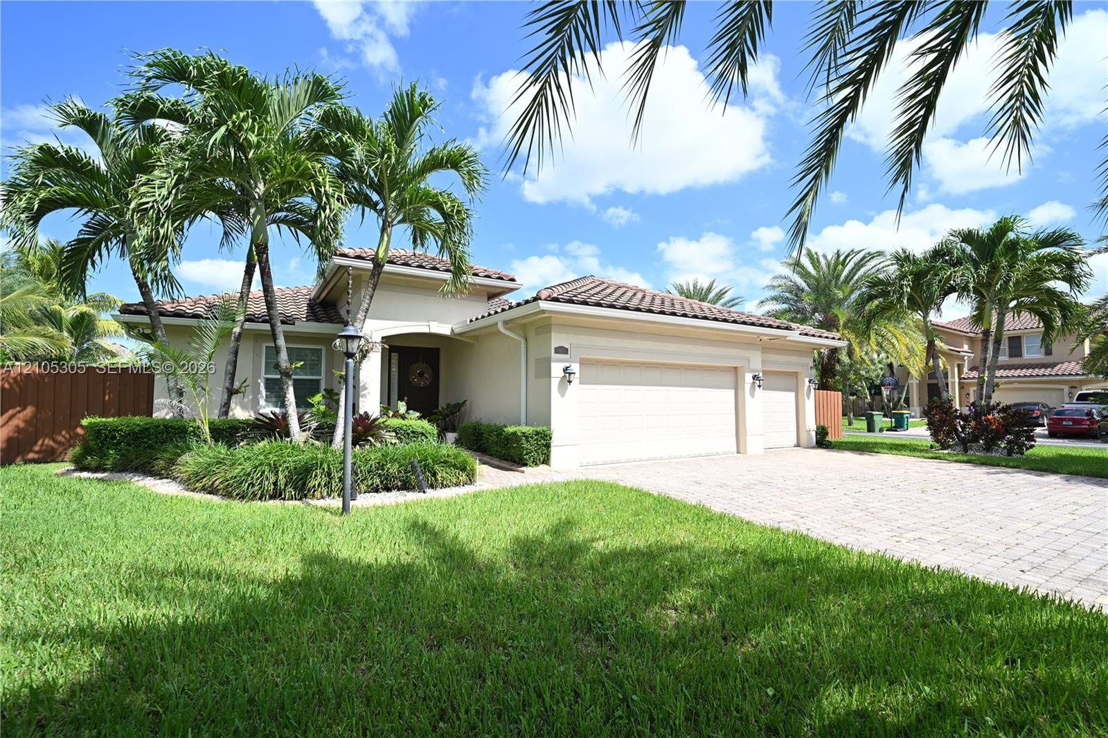 Stucco exterior with a tile roof, a two-car garage, and a paver driveway