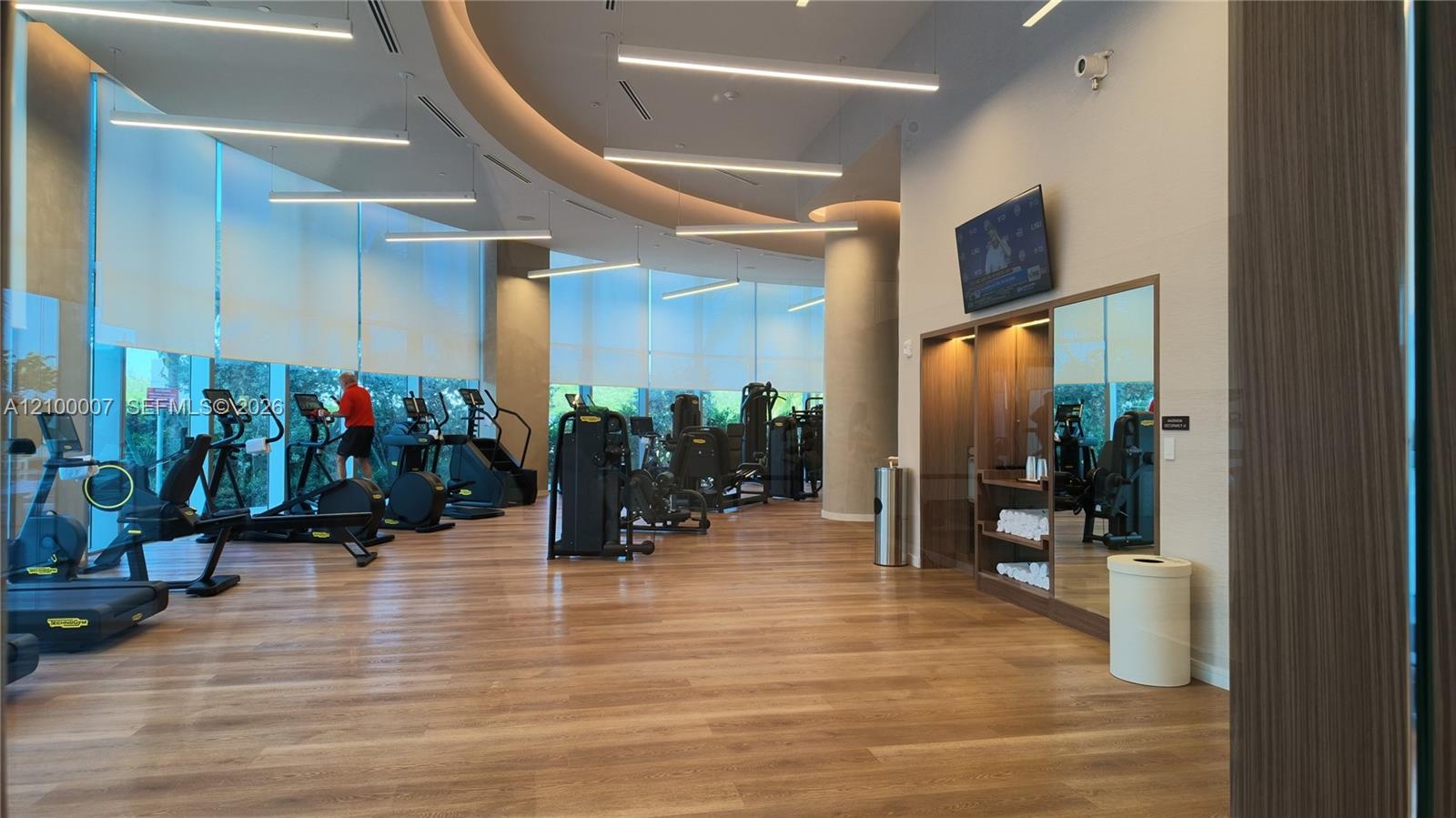 Fitness center featuring wood-finish flooring, full-height windows, and recessed linear lighting