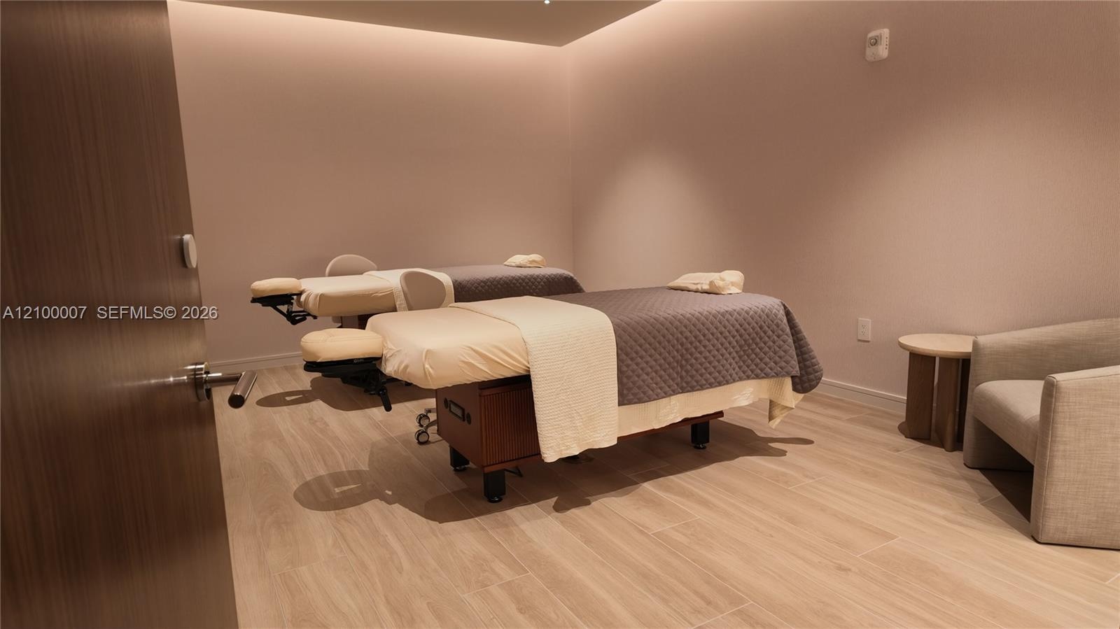 Wood-finish flooring with recessed ceiling lighting, textured wall finishes, and a contemporary light wood door