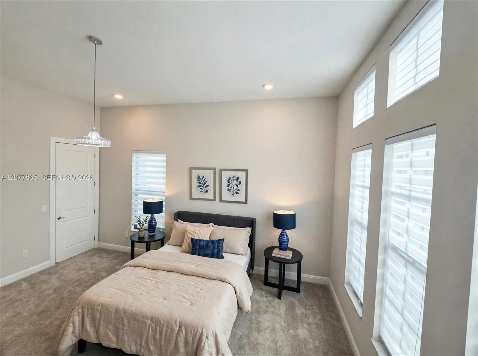 High ceilings with recessed lighting, carpet flooring, multiple windows with blinds, and a paneled interior door