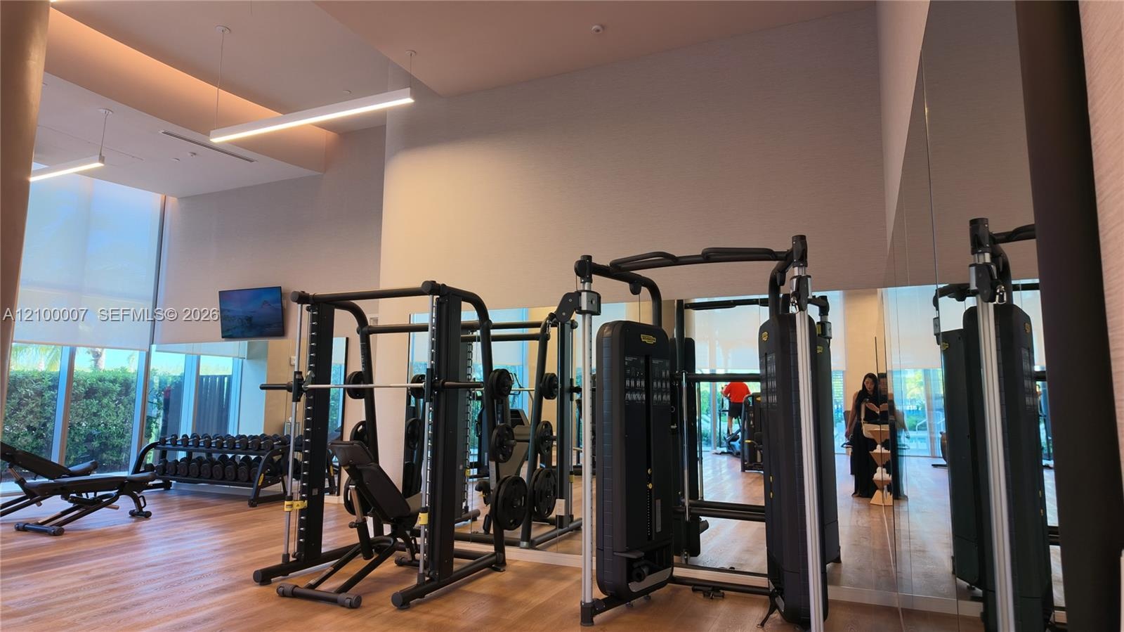 Fitness center featuring wood-finish flooring, high ceilings with recessed lighting, and expansive windows