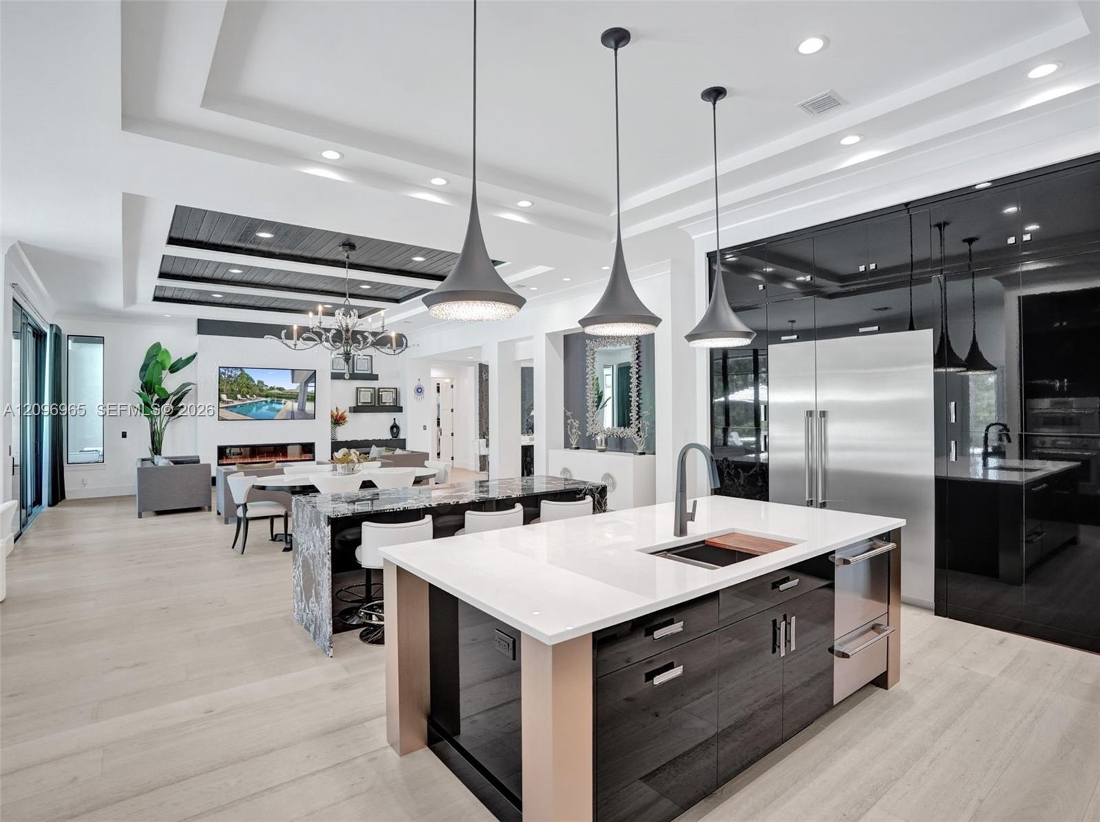 Tray ceiling with dark wood-finish plank detailing, linear electric fireplace, built-in display shelving, wood-finish flooring, and multi-panel slidin
