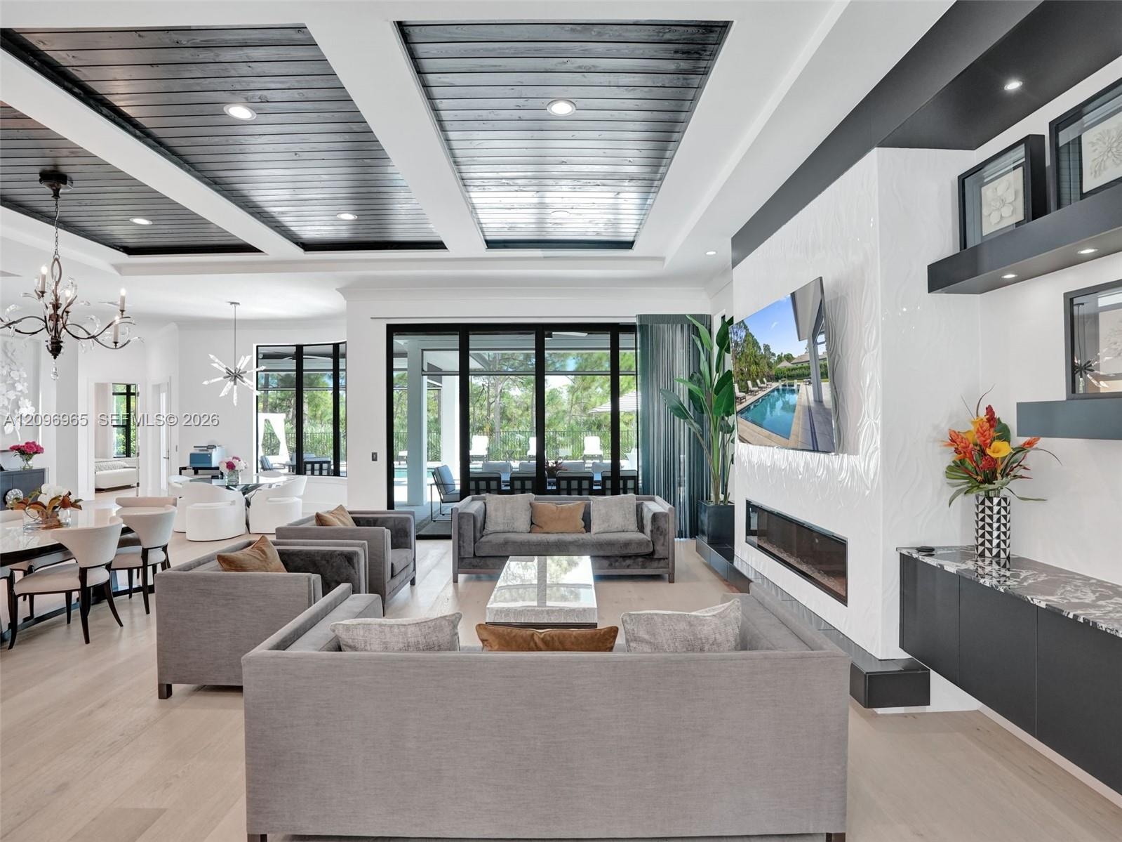 Curved staircase with black metal railing, built-in wet bar featuring stone-surface countertop, recessed lighting, plank-style flooring, and coffered 