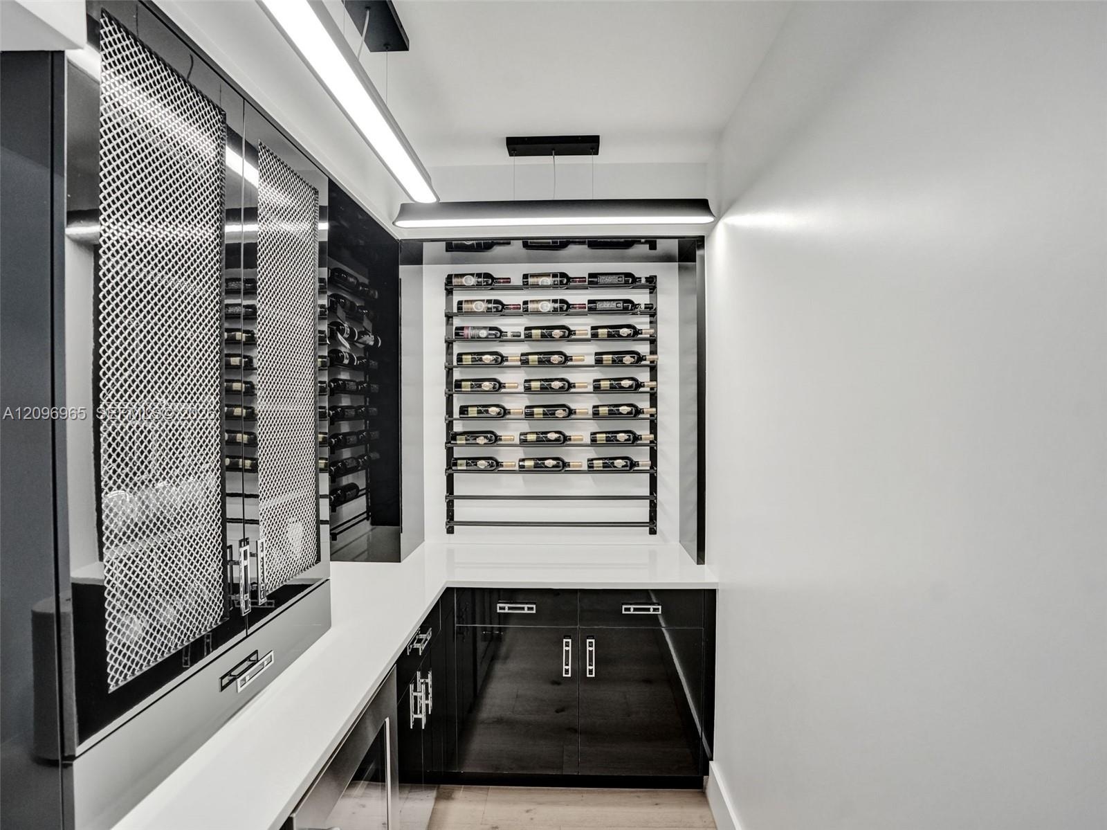Double-height foyer featuring a prominent floor-to-ceiling textured black tile accent wall, wood-finish flooring, and a metal horizontal-bar staircase