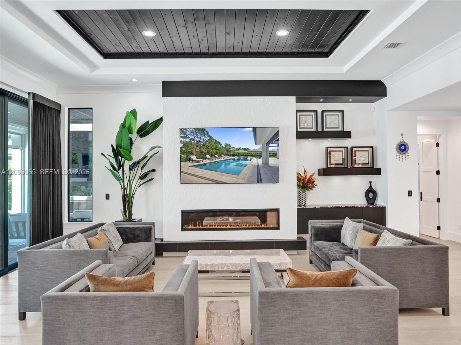 Coffered ceiling featuring dark wood-finish planking, linear fireplace with a textured surround, recessed lighting, multi-panel glass sliding doors, a