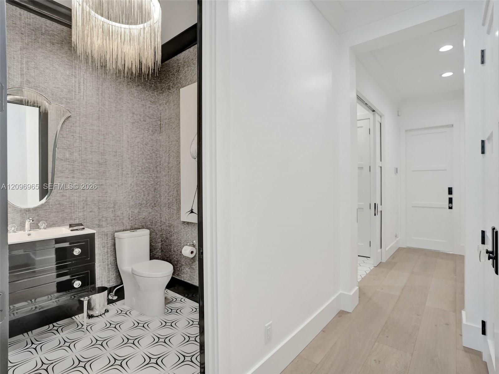 High-gloss black cabinetry, expansive white stone countertops, stainless steel professional-grade range with a matching range hood, and three oversize