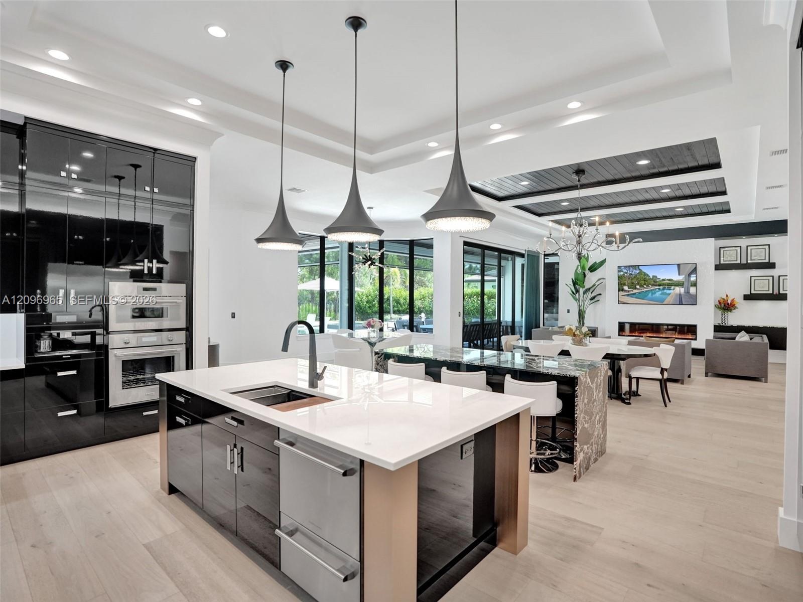 Tray ceiling with dark wood-finish planking, linear gas fireplace, built-in recessed shelving, integrated lighting, and light-toned flooring