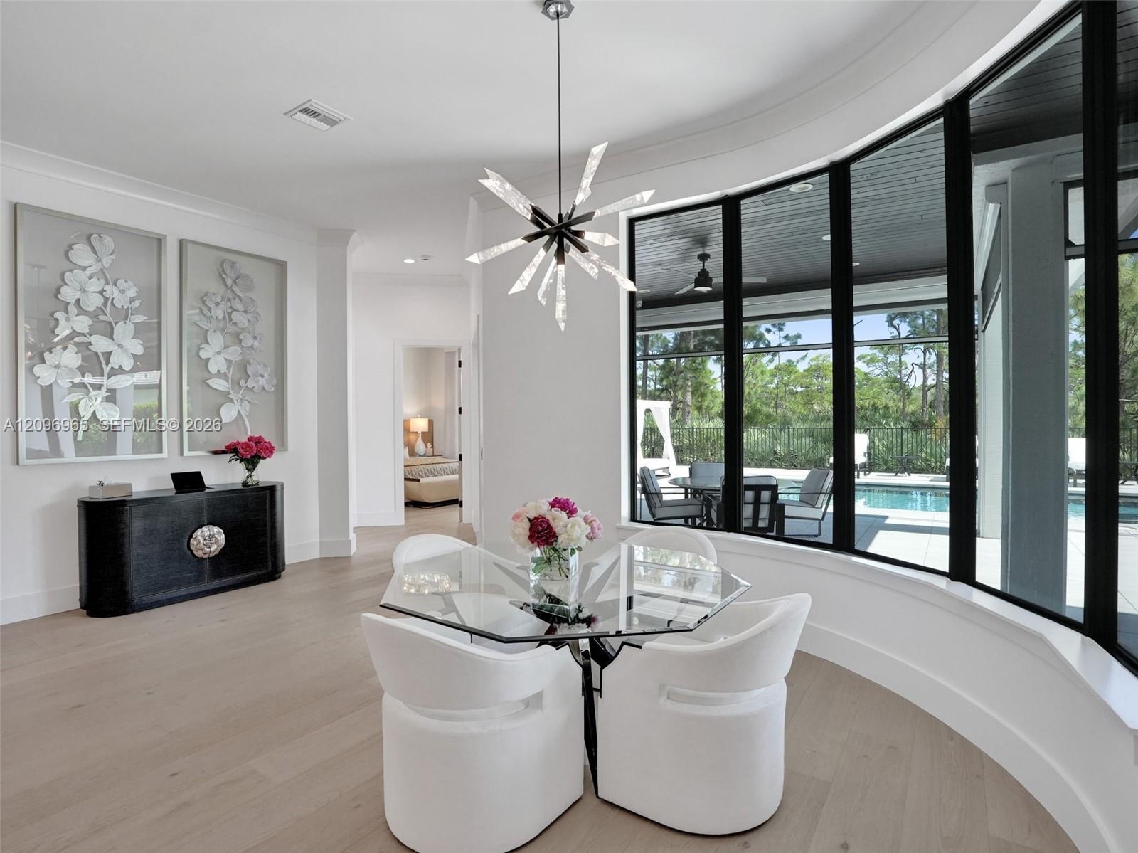 Modern kitchen featuring high-gloss black cabinetry, dual islands with contrasting surfaces, wood-finish flooring, recessed tray ceiling lighting, and