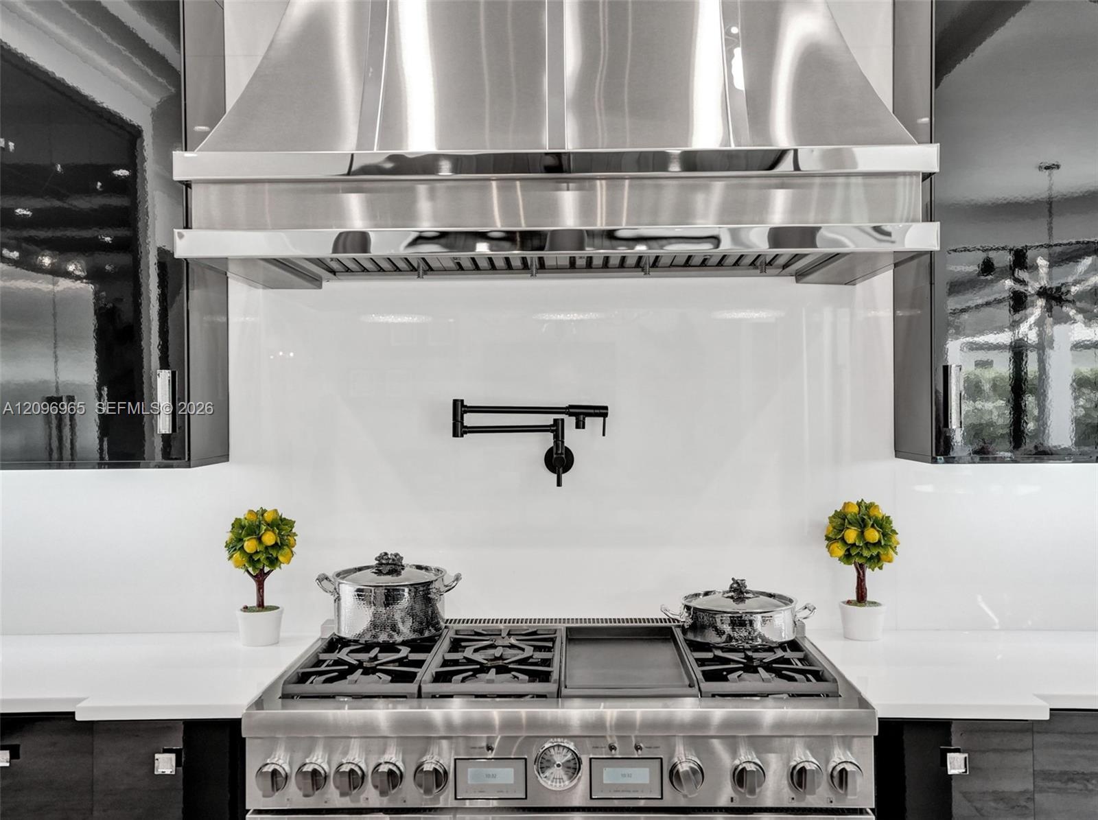 Custom wine display featuring horizontal metal racking, high-gloss black cabinetry, white countertops, and integrated linear lighting