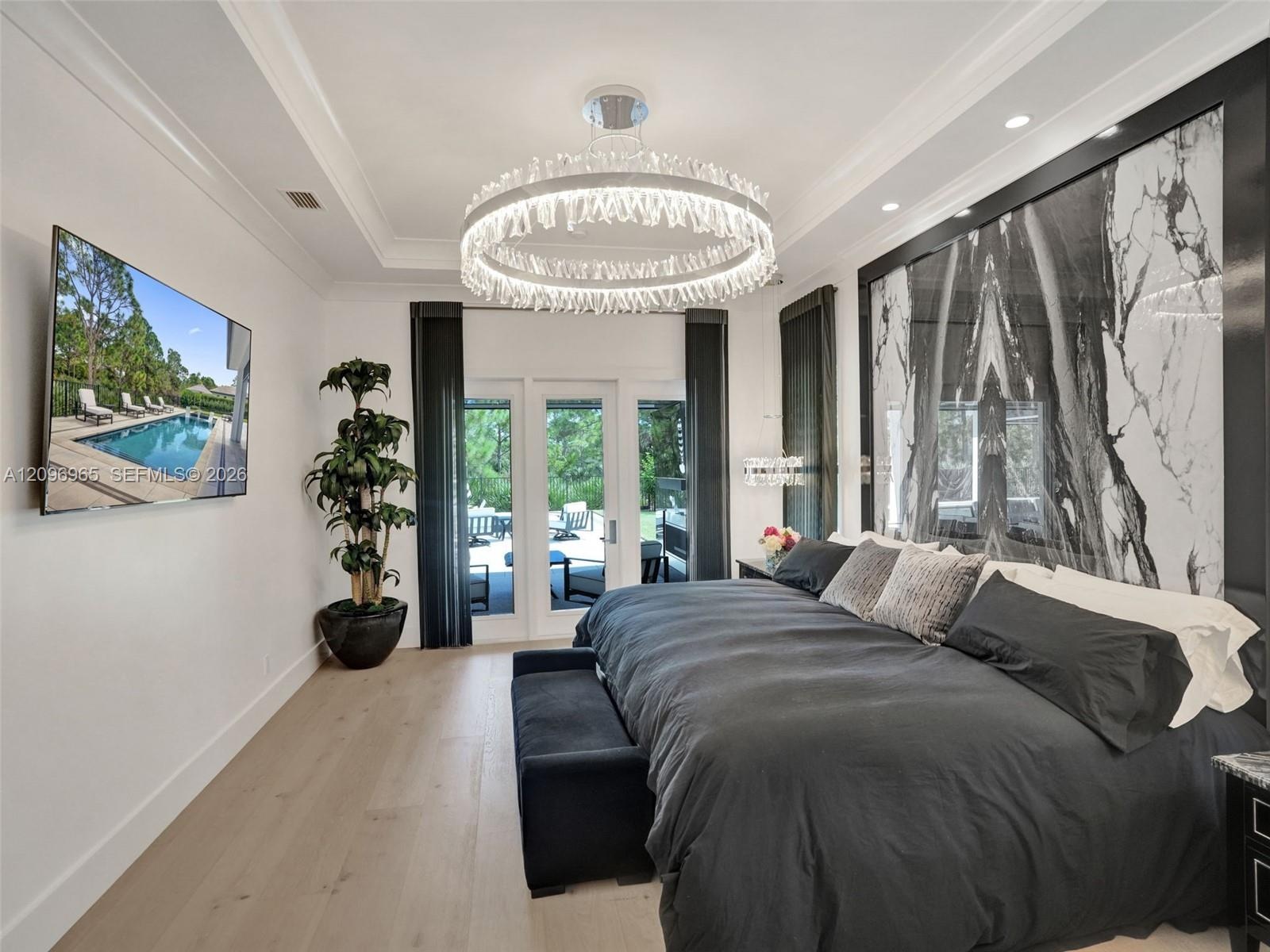 Kitchen featuring high-gloss cabinetry, stone-surface waterfall island with seating, wood-finish flooring, stainless steel appliances, and a recessed 