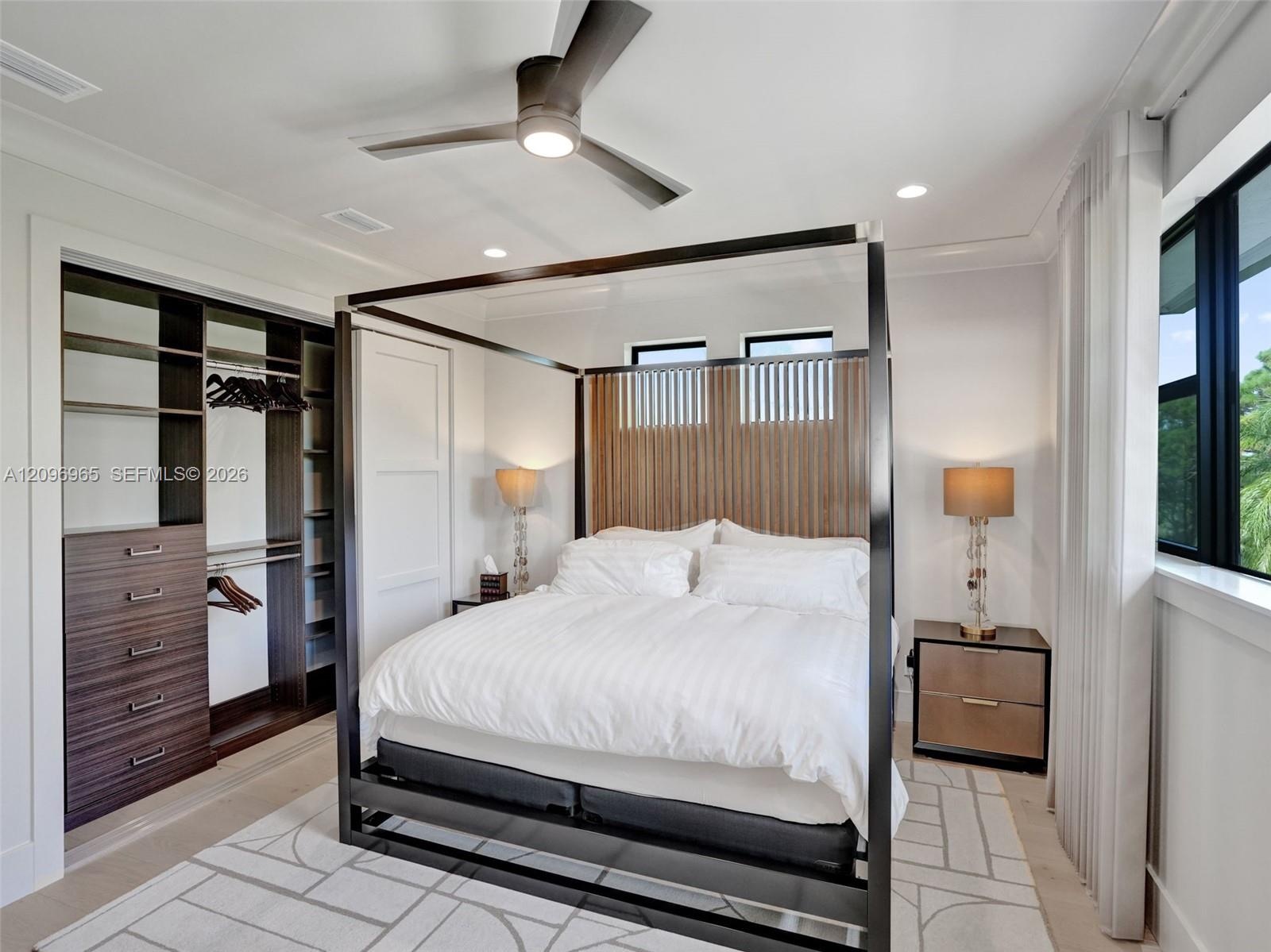 Full-height dramatic stone feature wall with integrated dark frame, circular tiered crystal chandelier, tray ceiling with recessed lighting, and wood-