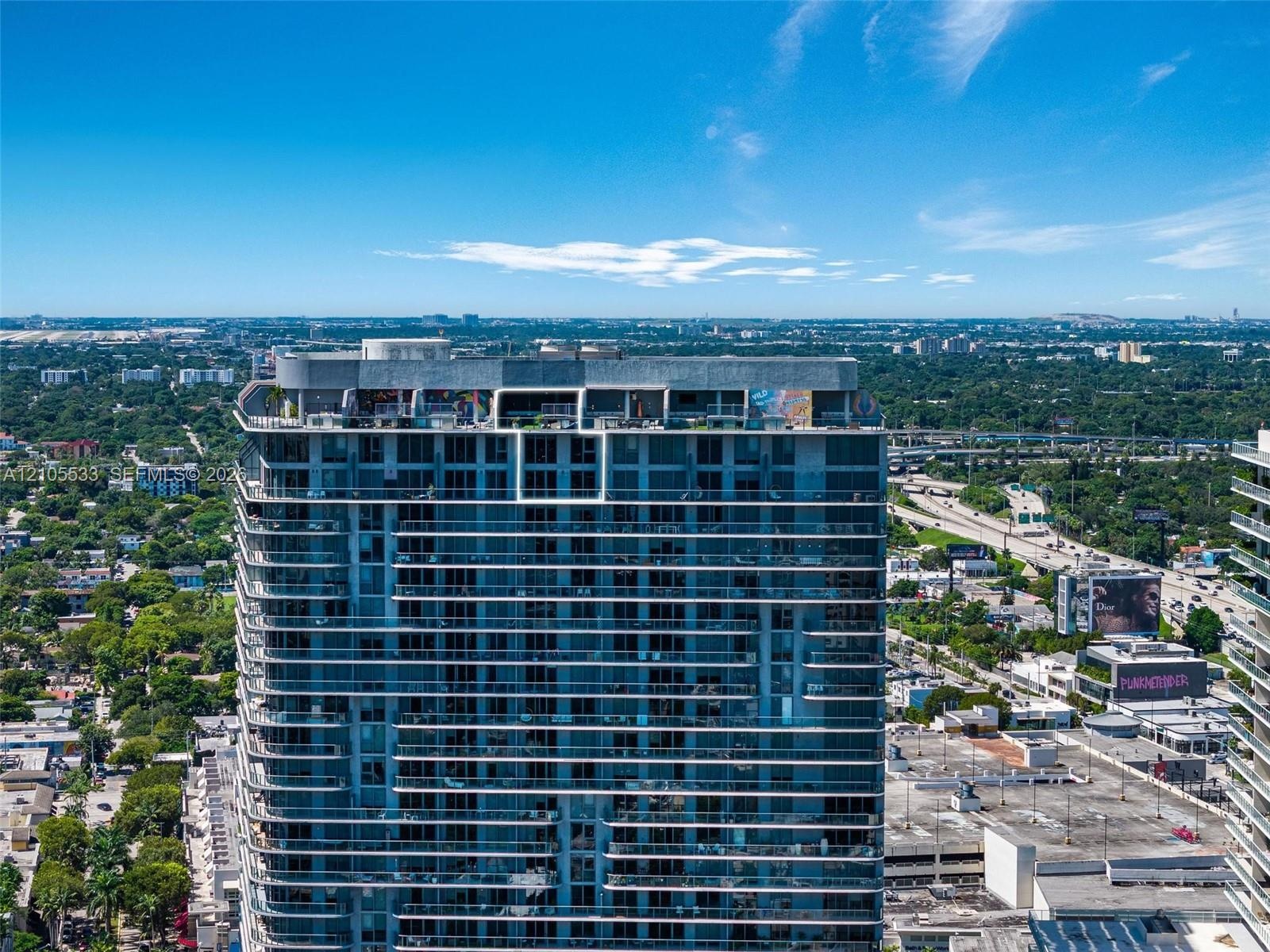 High-rise building featuring a glass facade, expansive horizontal balcony tiers, and a rooftop terrace