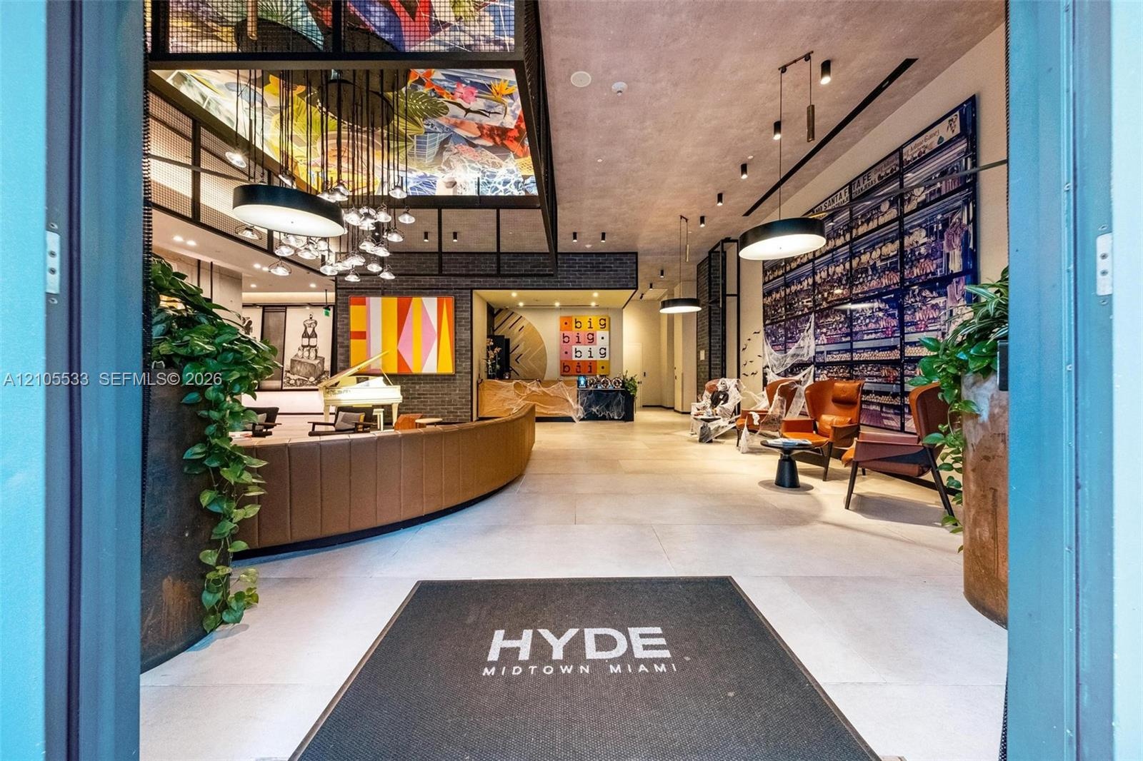 Lobby featuring large-scale ceiling artwork, a curved reception desk, custom pendant lighting, expansive tile flooring, and integrated wall installati