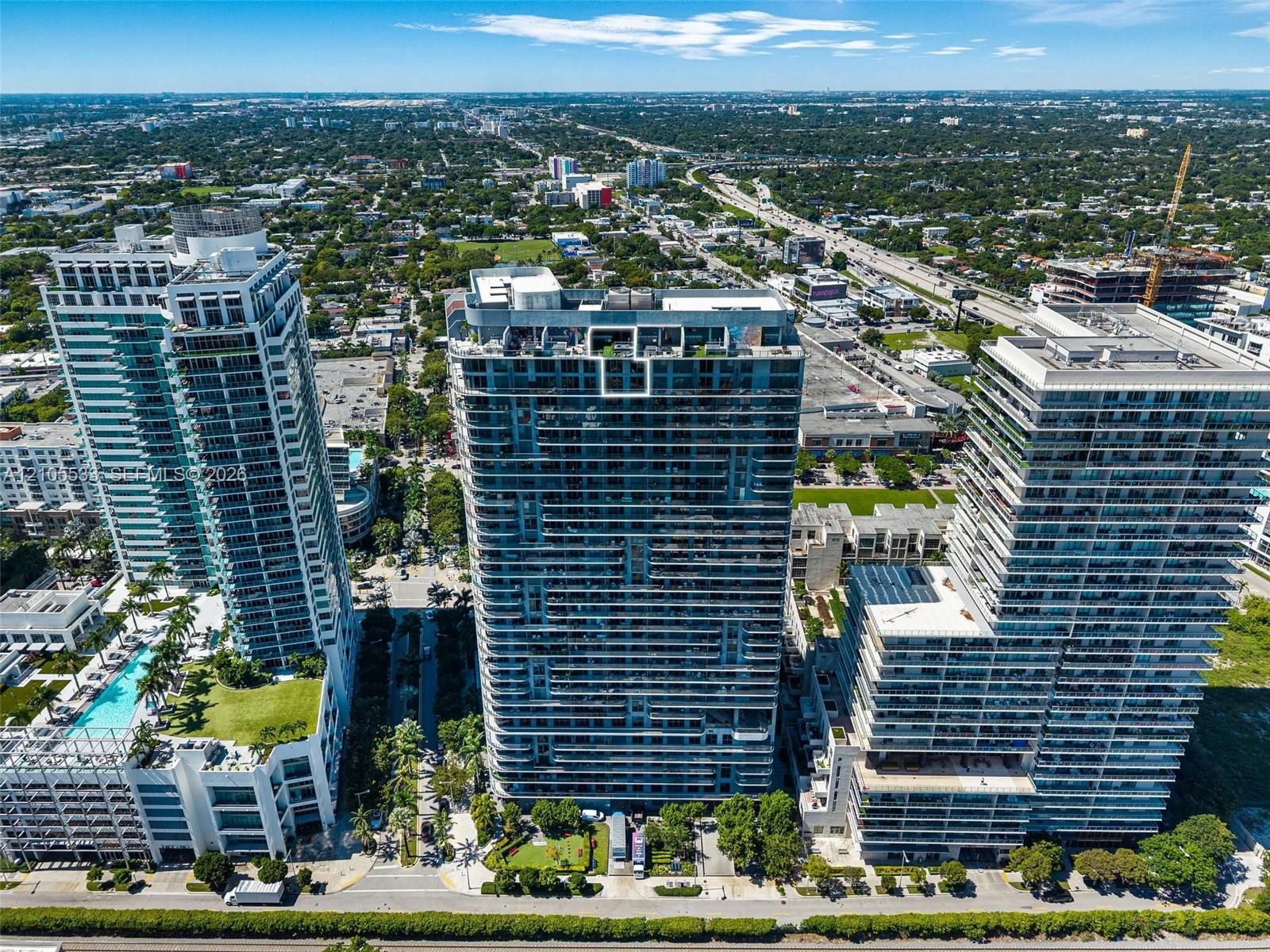 High-rise residential towers featuring glass-paneled balconies, expansive floor-to-ceiling windows, and rooftop terrace levels