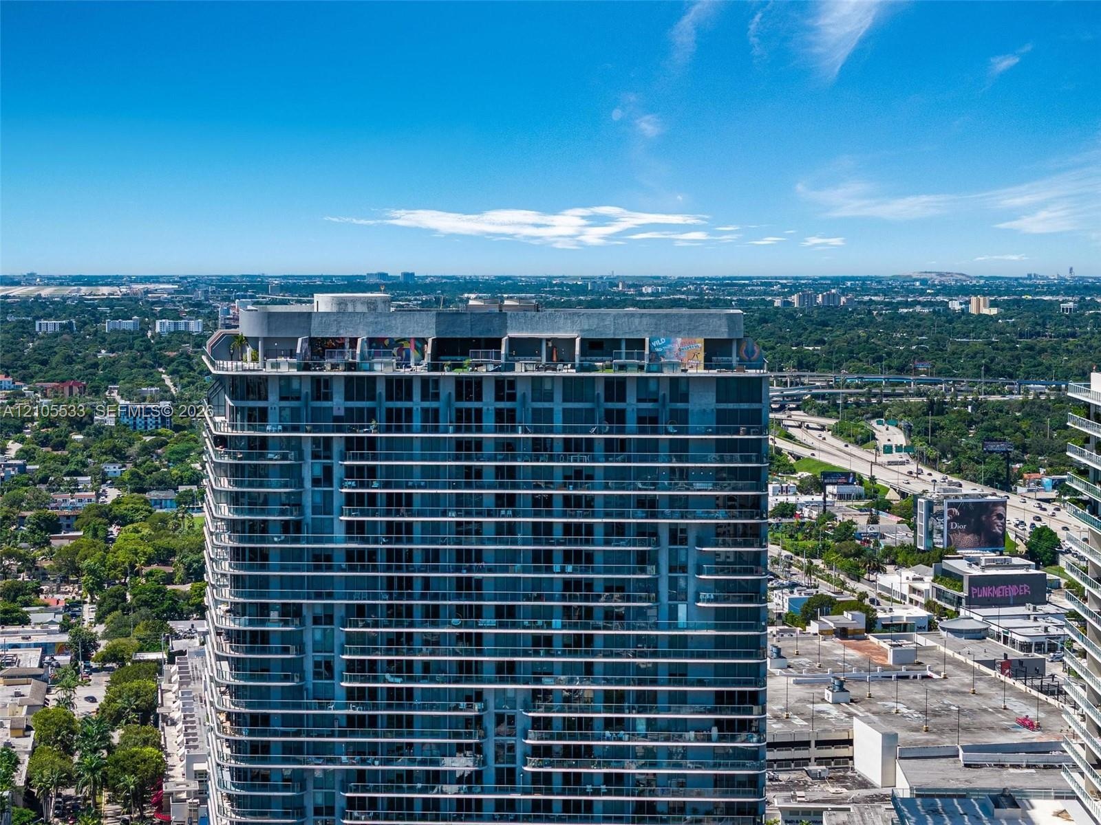 High-rise building featuring a glass facade, expansive wrap-around balconies, and a finished rooftop terrace