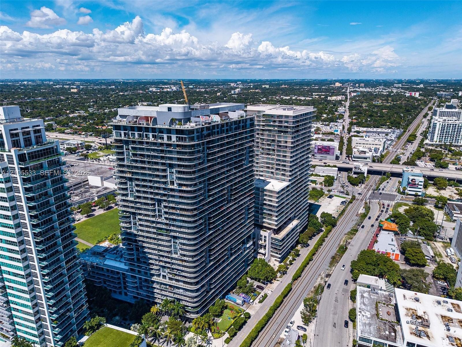 High-rise residential towers featuring wrap-around balconies, glass-paneled railings, exterior concrete structural elements, rooftop recreational spac
