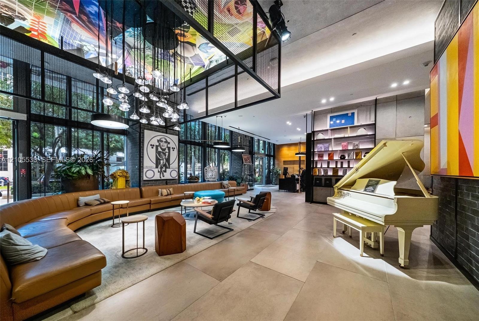 Expansive lobby featuring floor-to-ceiling windows, large-format tile flooring, industrial-style grid ceiling structure with integrated lighting, and 
