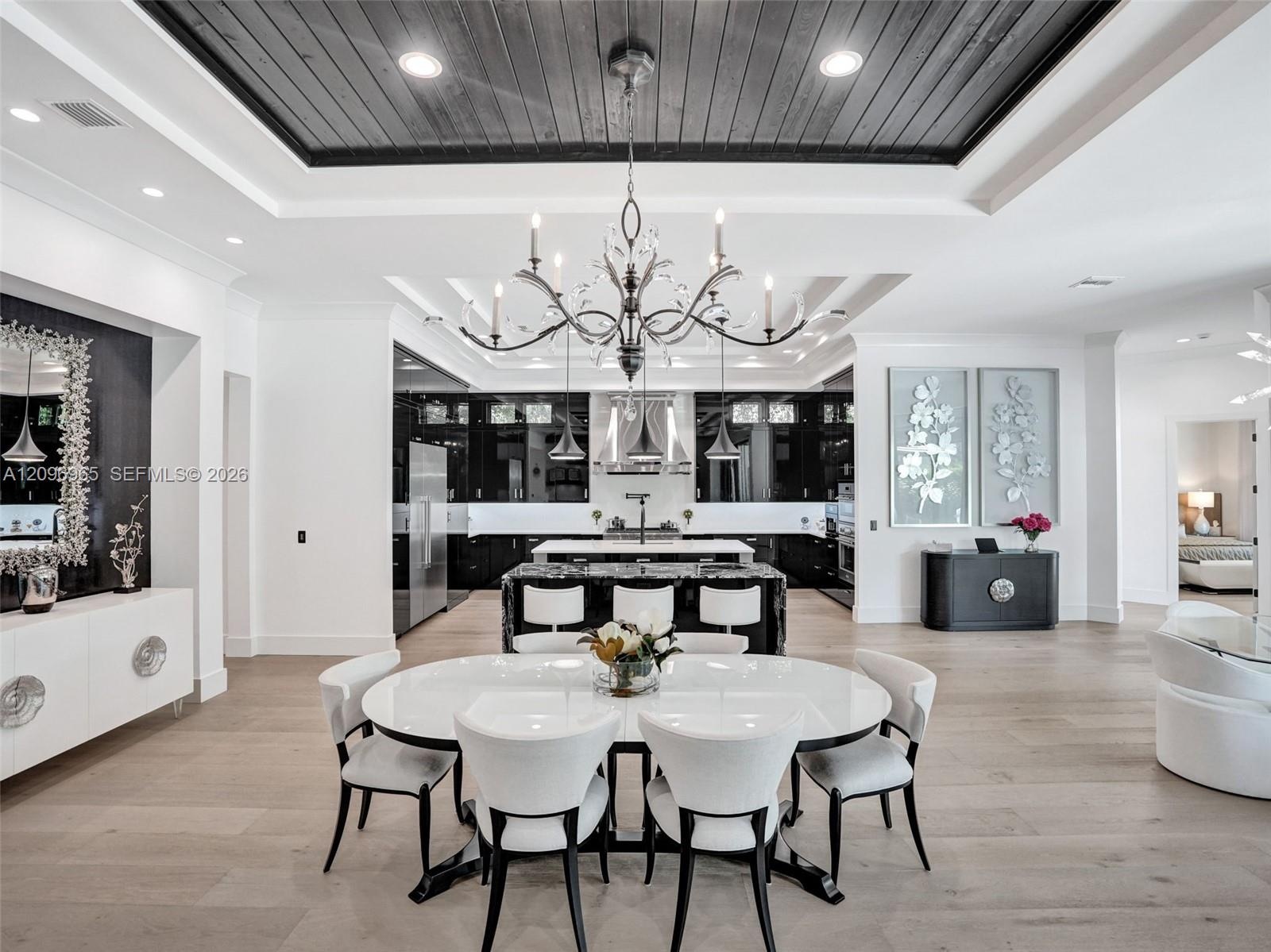 Linear fireplace with textured surround, coffered ceiling featuring dark wood-finish accents, light-tone wood-finish flooring, built-in bar cabinetry,