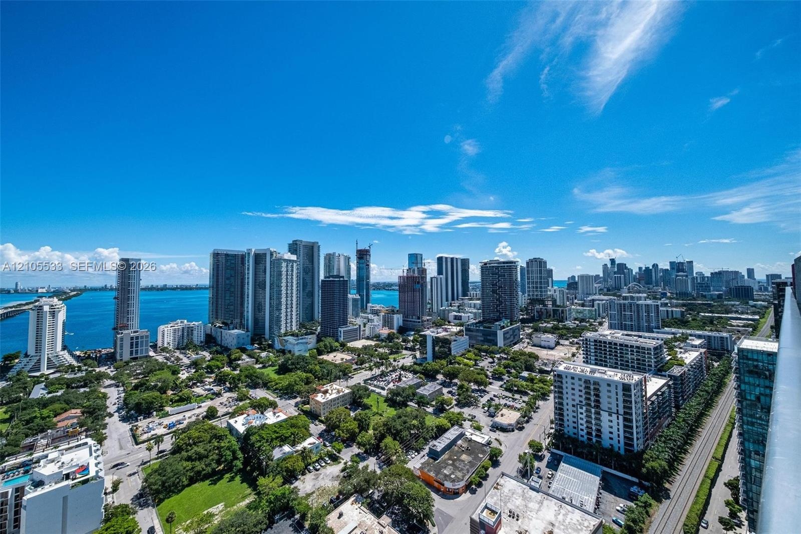 Elevated balcony perspective featuring glass railing, panoramic city skyline, and waterfront scenery