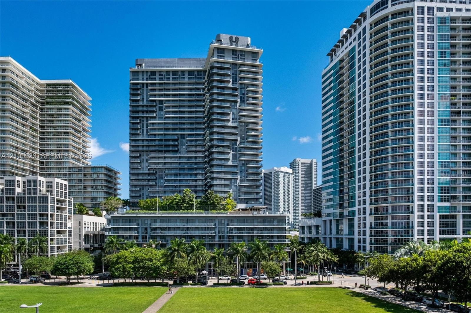 High-rise residential tower featuring glass facade construction, expansive private balconies, and landscaped podium-level terrace
