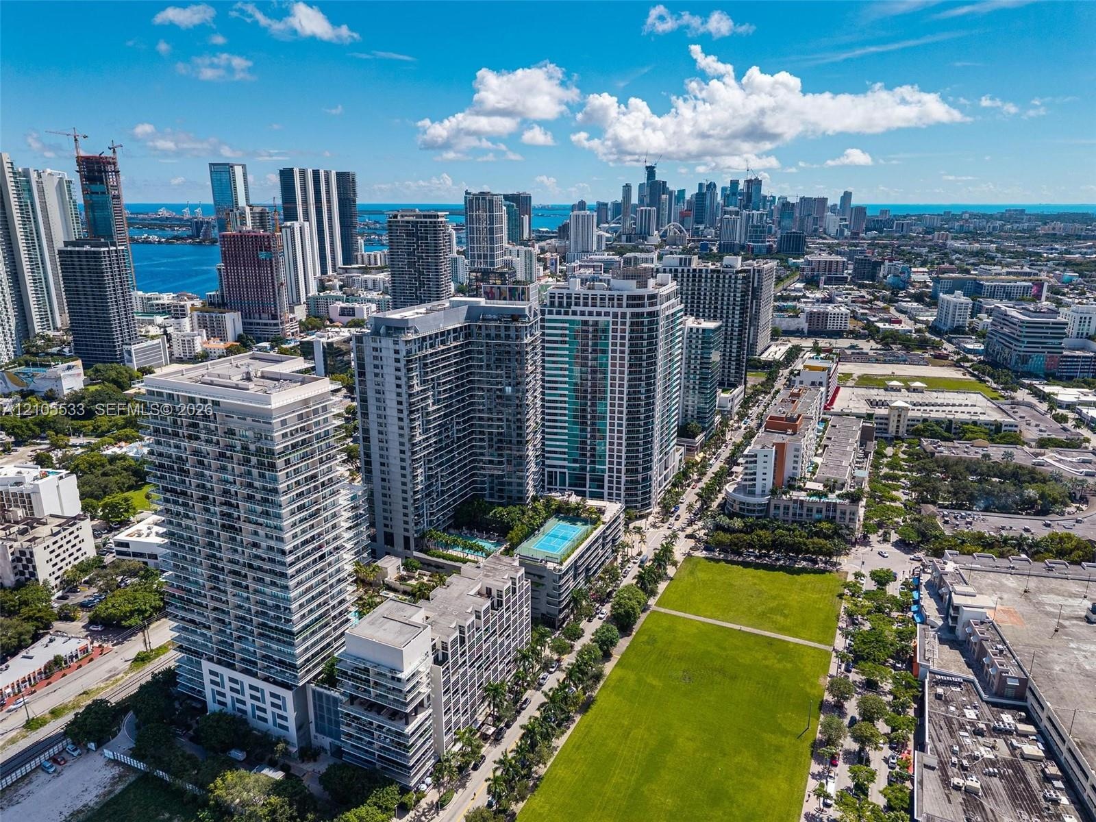 Aerial perspective featuring high-rise urban structures, a large green space, and proximity to metropolitan waterfronts