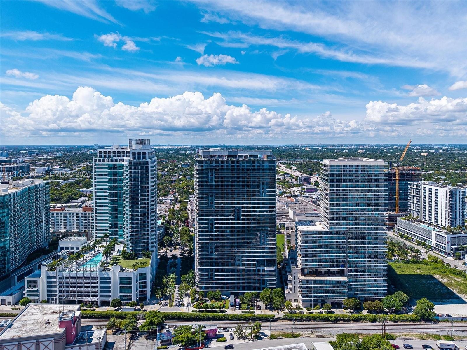 Aerial perspective of a high-rise urban landscape featuring glass-facade residential towers, expansive horizontal balconies, and incorporated podium-l