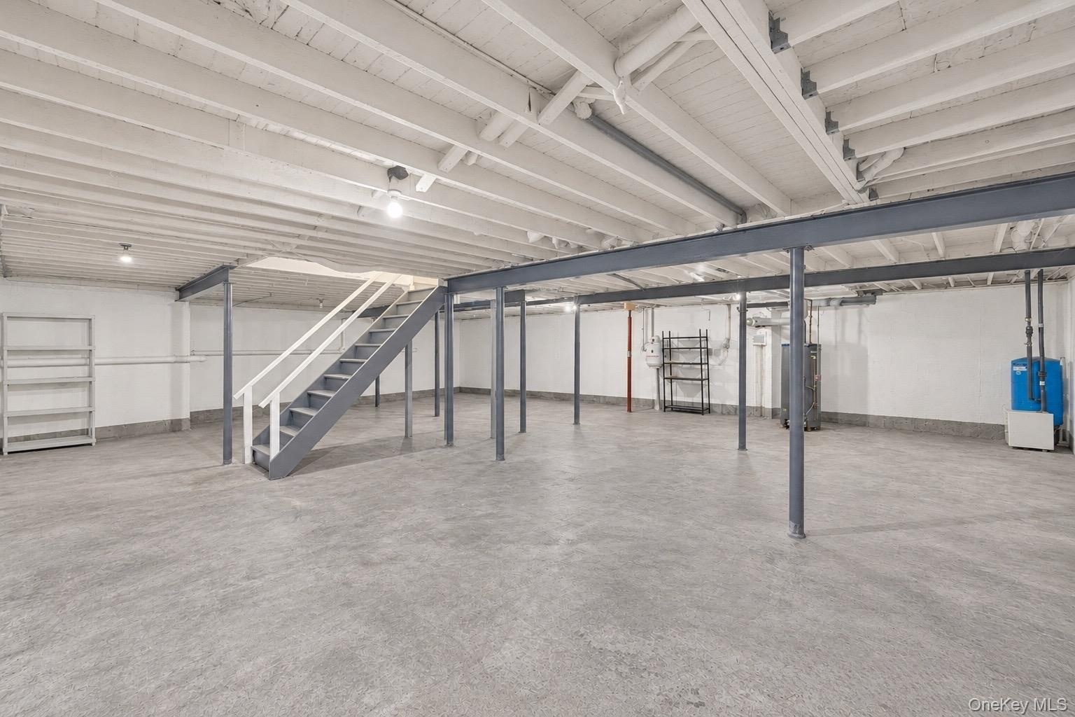 Unfinished basement with 9 ft ceilings. Open-concept lower level featuring exposed ceiling joists, concrete flooring, steel support beams, and painted