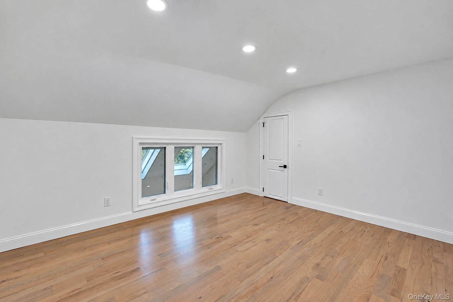 2nd floor Bedroom featuring wood-finish flooring, sloped ceilings, recessed lighting, and a multi-pane window with white trim