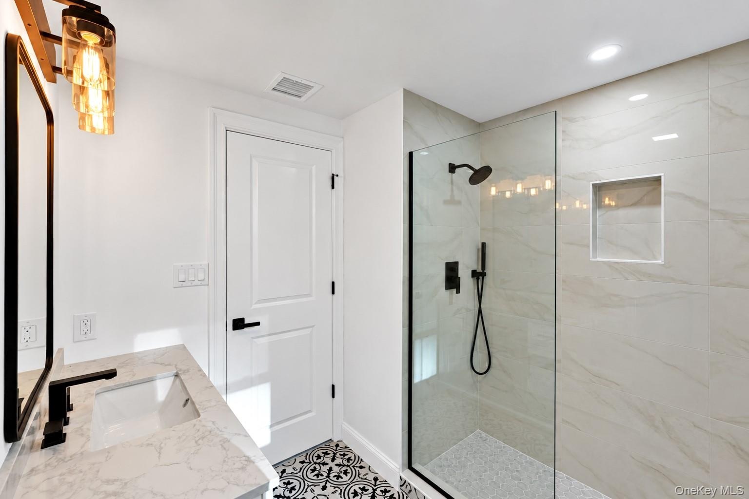 2nd floor Bathroom featuring a stone-look countertop with an integrated rectangular sink, walk-in shower with large-format wall tile and built-in nich