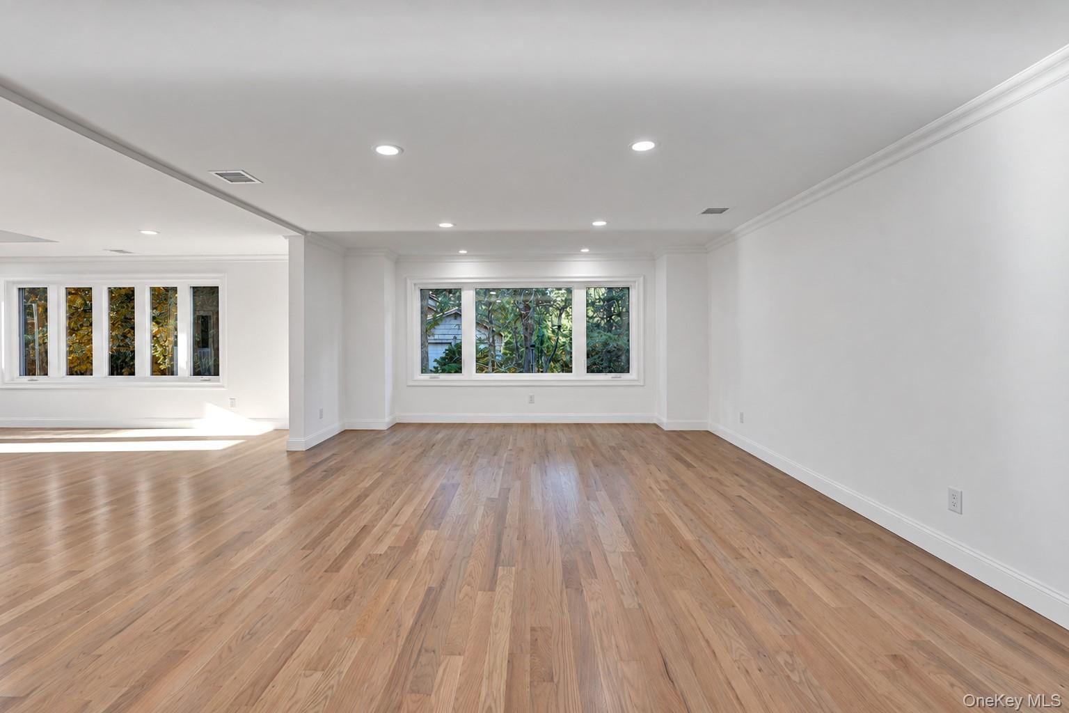 Open-concept space featuring wood-finish flooring, multi-pane windows, crown molding, and recessed lighting