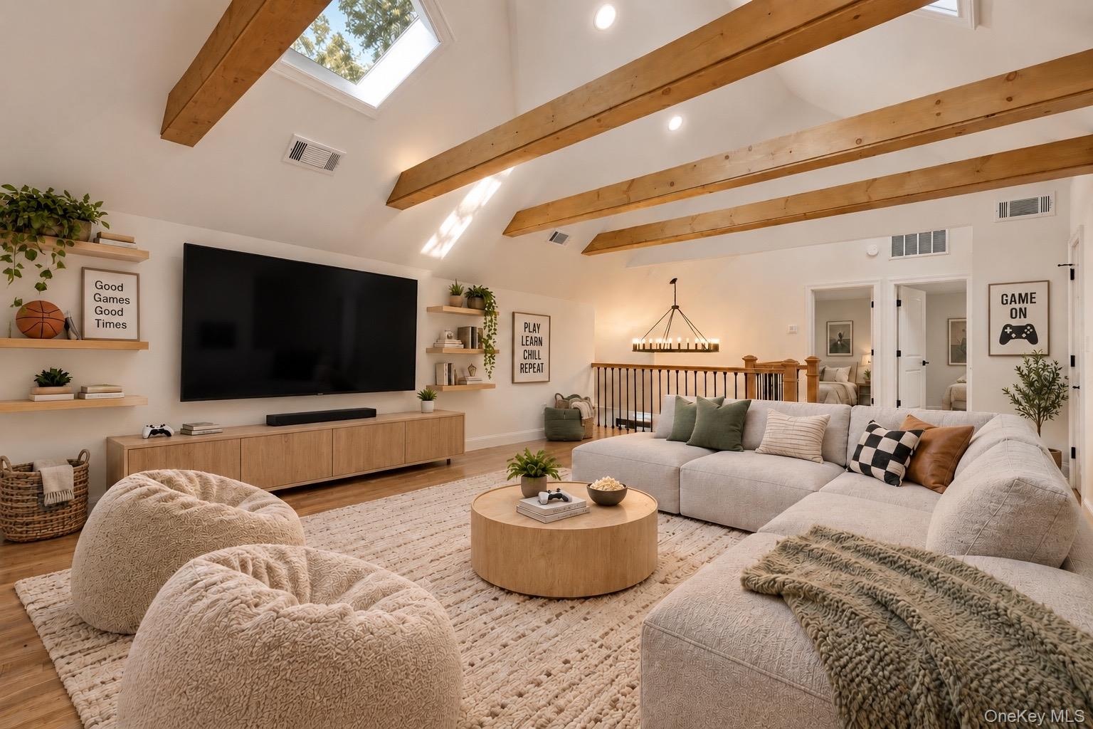 2nd floor loft. Vaulted ceiling with exposed wood beams, skylights, built-in wall shelving, wood-finish flooring, and a multi-light chandelier