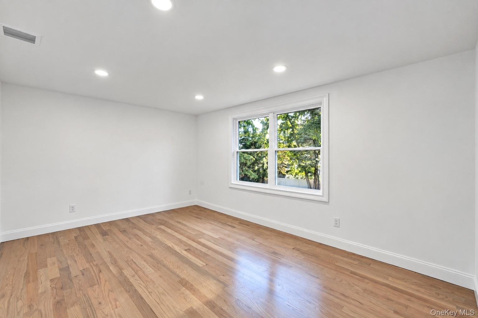 2nd floor bedroom featuring wood-finish flooring, recessed lighting, and a multi-pane window
