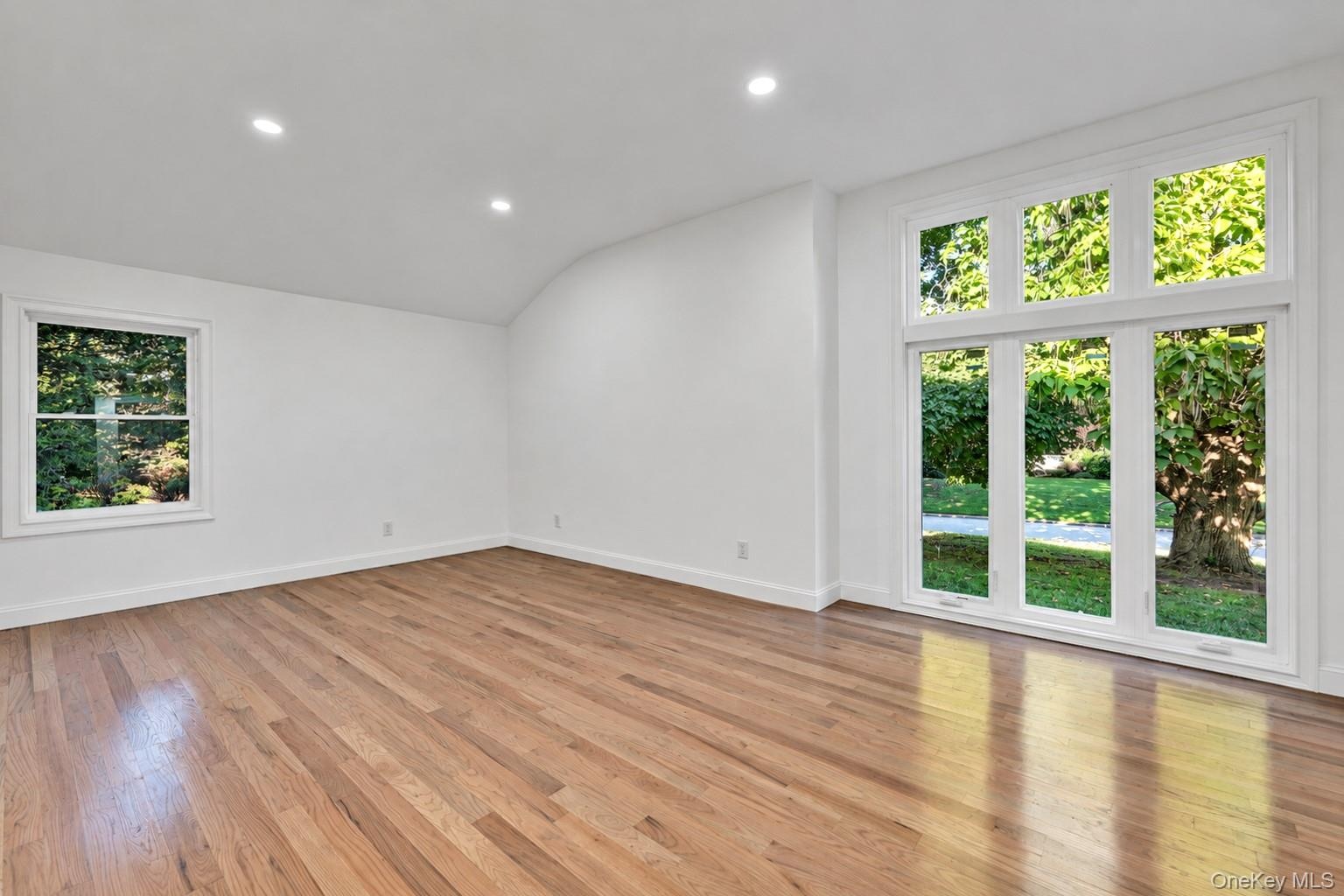 Interior space featuring polished wood-finish flooring, recessed lighting, and a vaulted ceiling