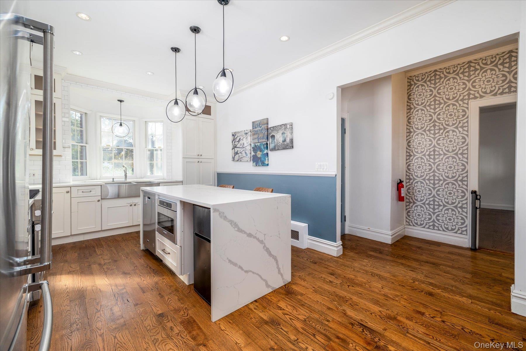 updated kitchen, center island with waterfall countertops and stainless steel appliances.