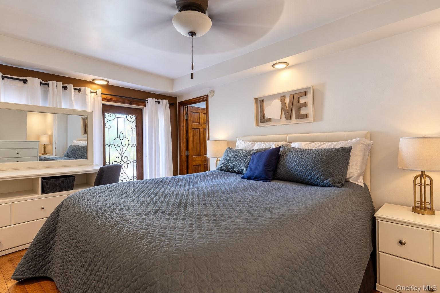 Tray ceiling with recessed lighting, ceiling fan, wood-finish flooring, built-in cabinetry, and decorative iron-detail exterior door